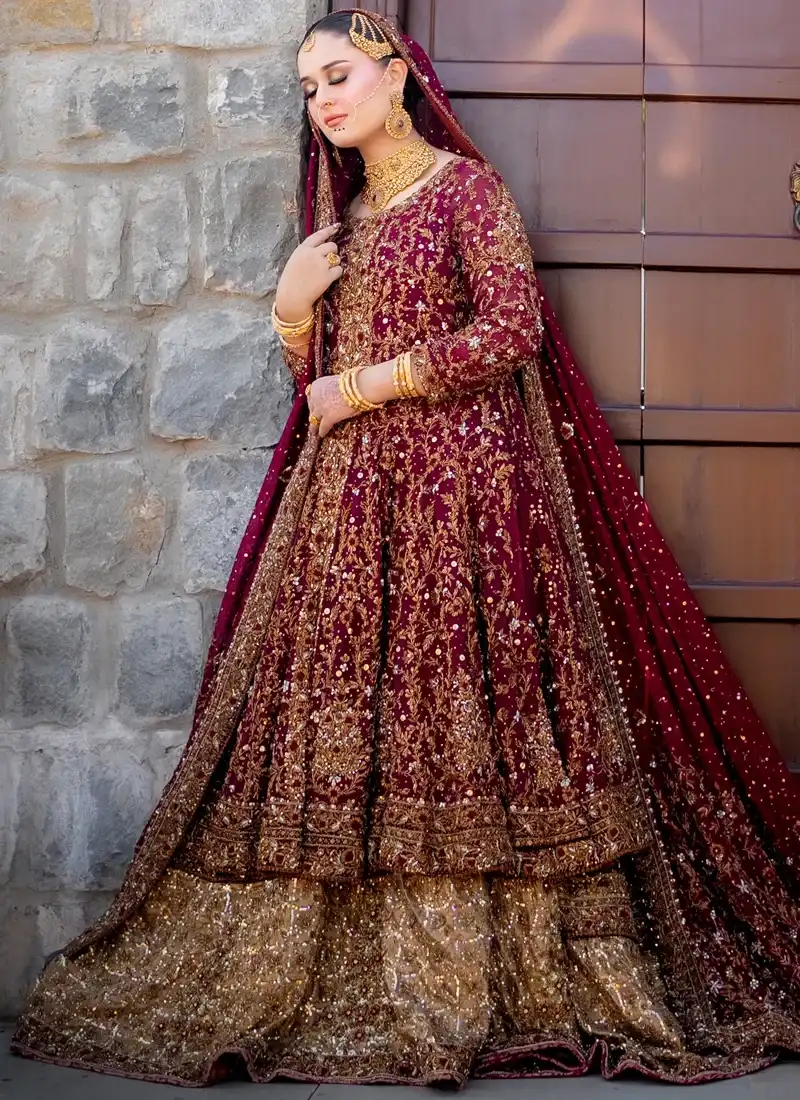 Burgundy Baraat Farshi Lehenga with Front-Slit Gown Burgundy bridal gown side view with gold floral vines and a bronze-gold flared lehenga