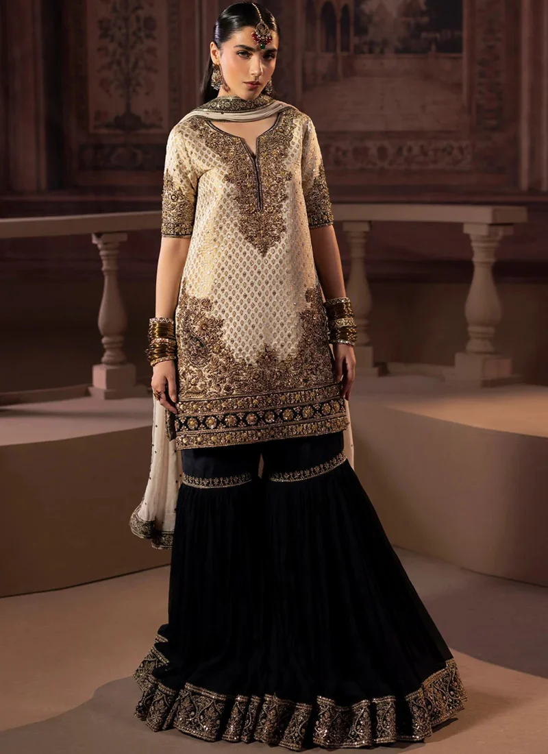 Ivory Walima Gharara Suit with Paisley Flounce Borders Ivory and black gharara suit, full front view, with gold embroidery and paisley borders on the flared hem