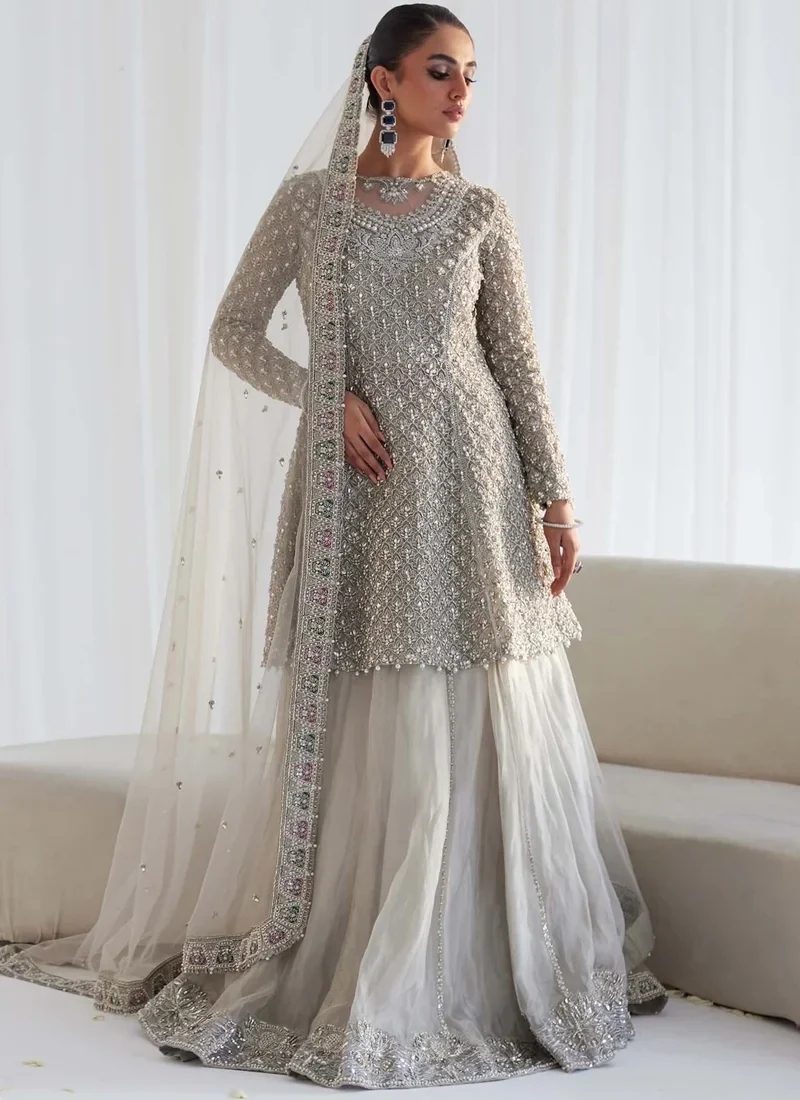 Silver Nikkah Frock with Lehenga with Pastel Tile Dupatta Border Silver Nikkah frock with lehenga in seated front view showing a wide embroidered hem and flowing dupatta